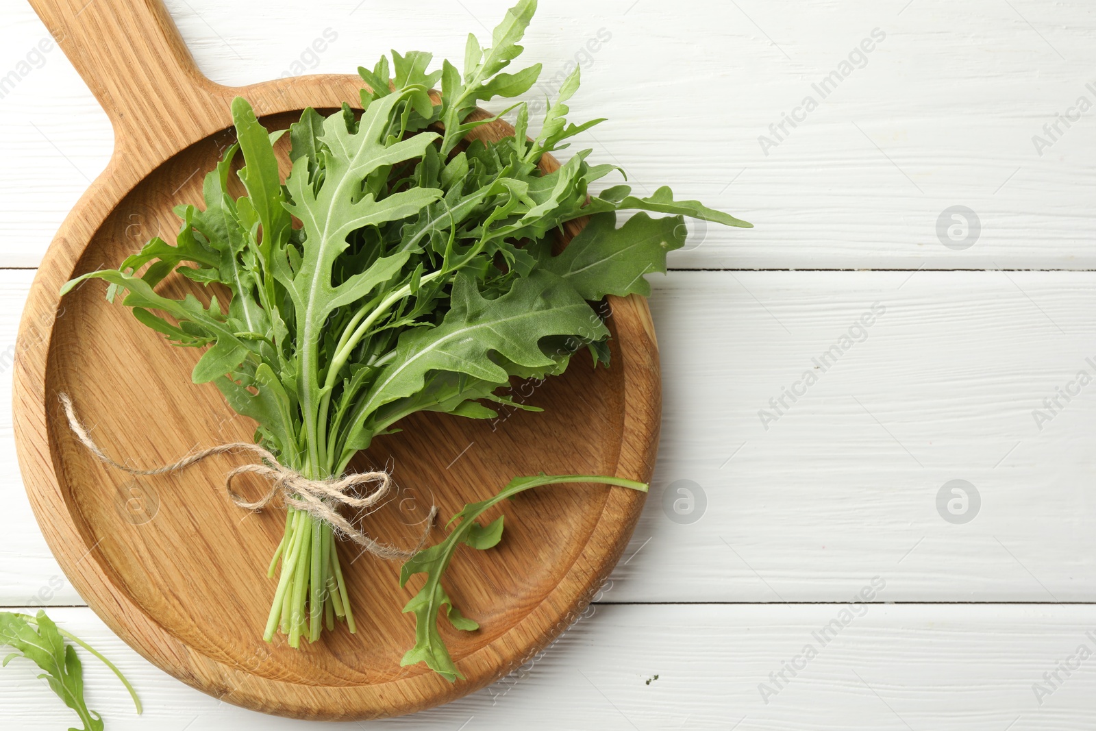 Photo of Bunch of fresh green arugula leaves on white wooden table, top view. Space for text