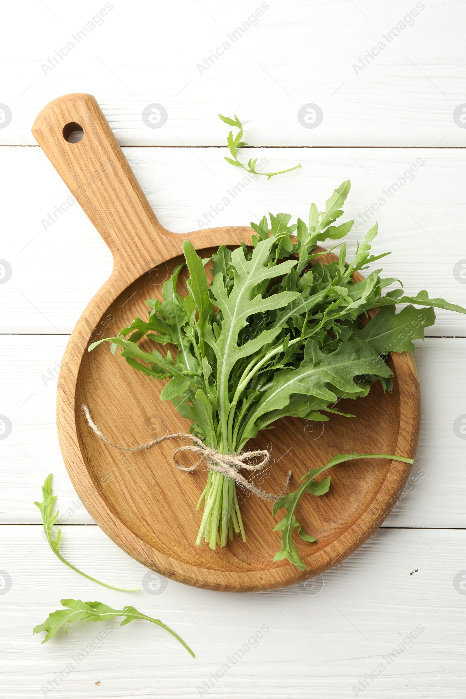 Photo of Bunch of fresh green arugula leaves on white wooden table, top view