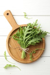 Photo of Bunch of fresh green arugula leaves on white wooden table, top view