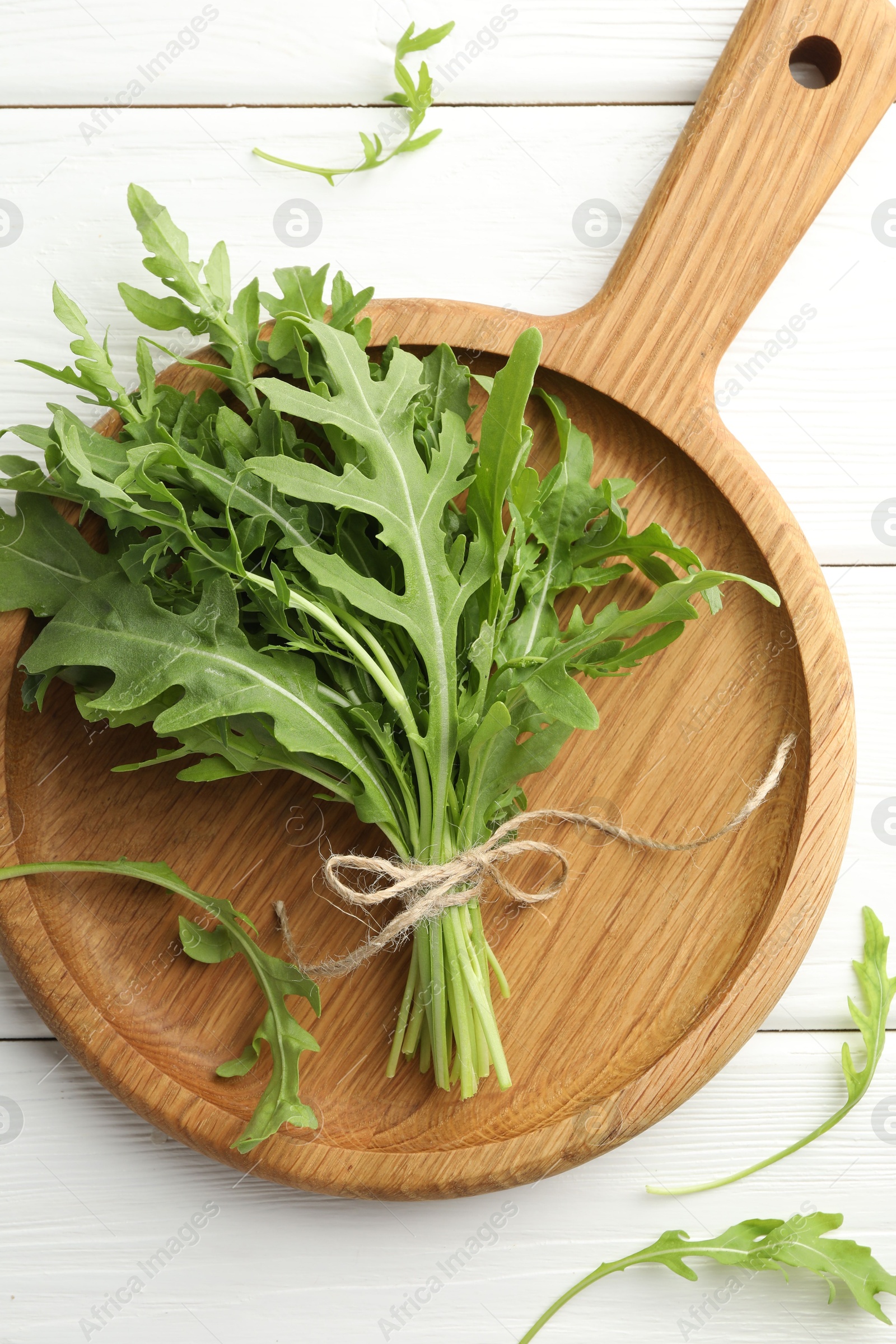 Photo of Bunch of fresh green arugula leaves on white wooden table, top view