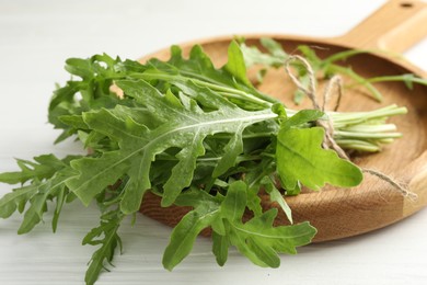 Photo of Bunch of fresh green arugula leaves on white wooden table, closeup