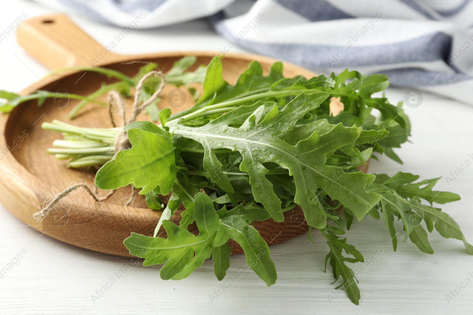 Photo of Bunch of fresh green arugula leaves on white wooden table, closeup