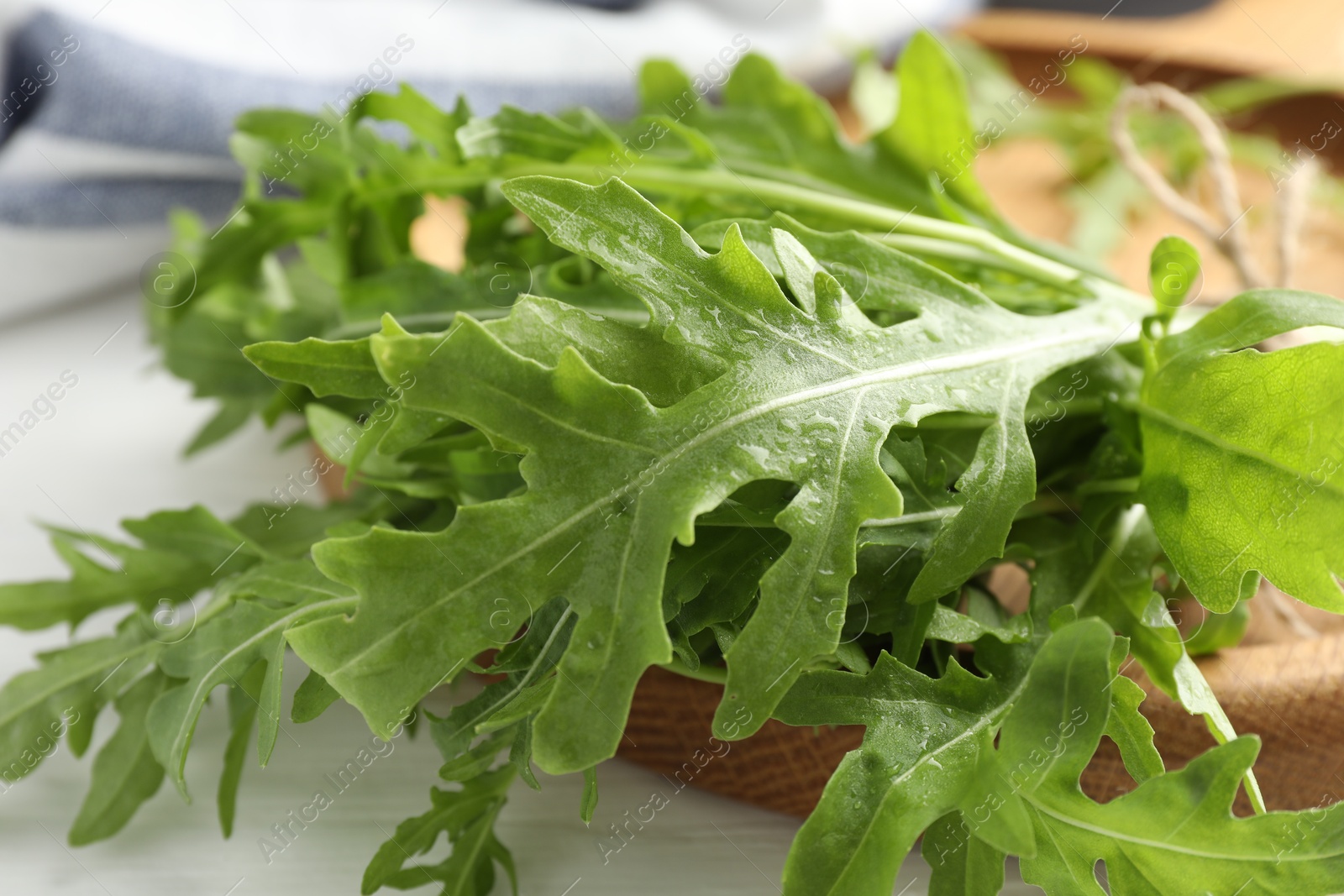 Photo of Fresh green arugula leaves on white table, closeup