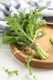 Photo of Bunch of fresh green arugula leaves on white wooden table, closeup