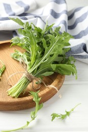 Photo of Bunch of fresh green arugula leaves on white wooden table, closeup