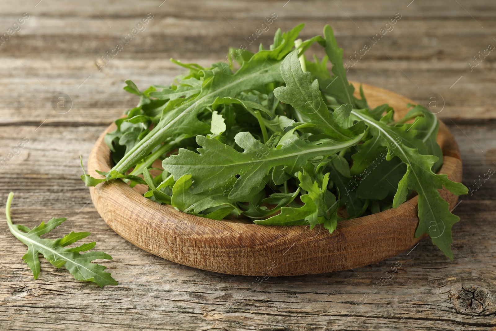 Photo of Fresh green arugula leaves on wooden table, closeup