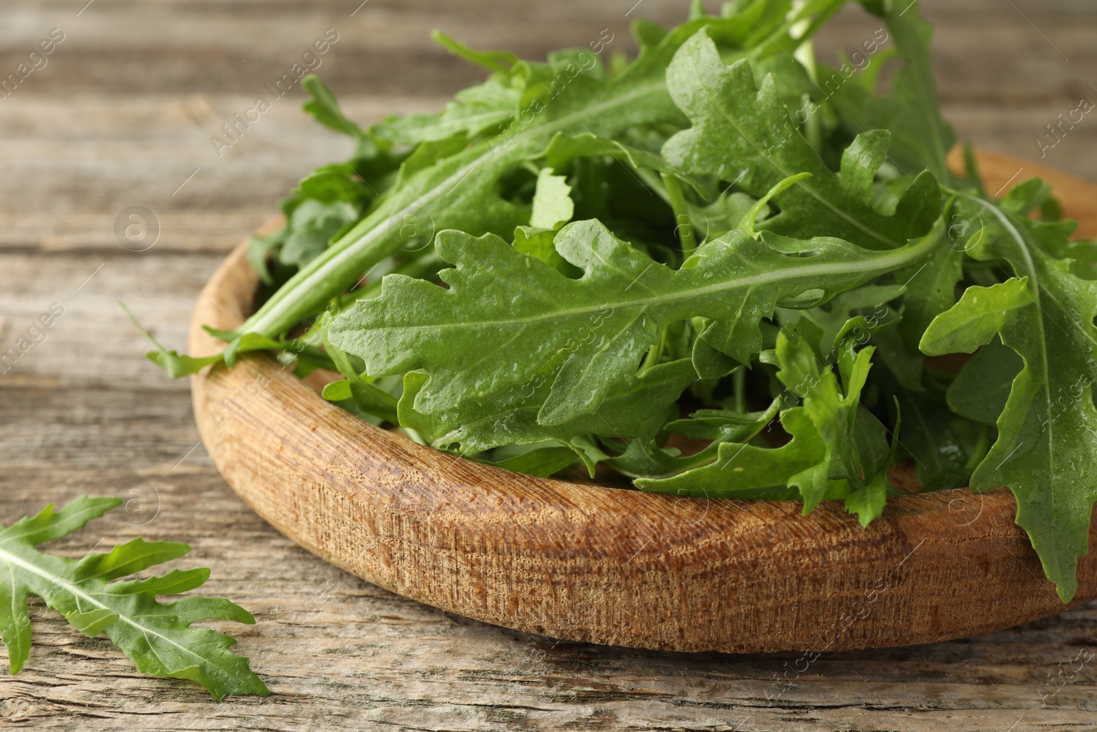 Photo of Fresh green arugula leaves on wooden table, closeup