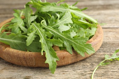 Photo of Fresh green arugula leaves on wooden table, closeup