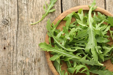 Photo of Fresh green arugula leaves on wooden table, top view. Space for text