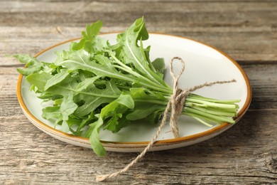 Photo of Bunch of fresh green arugula leaves on wooden table, closeup