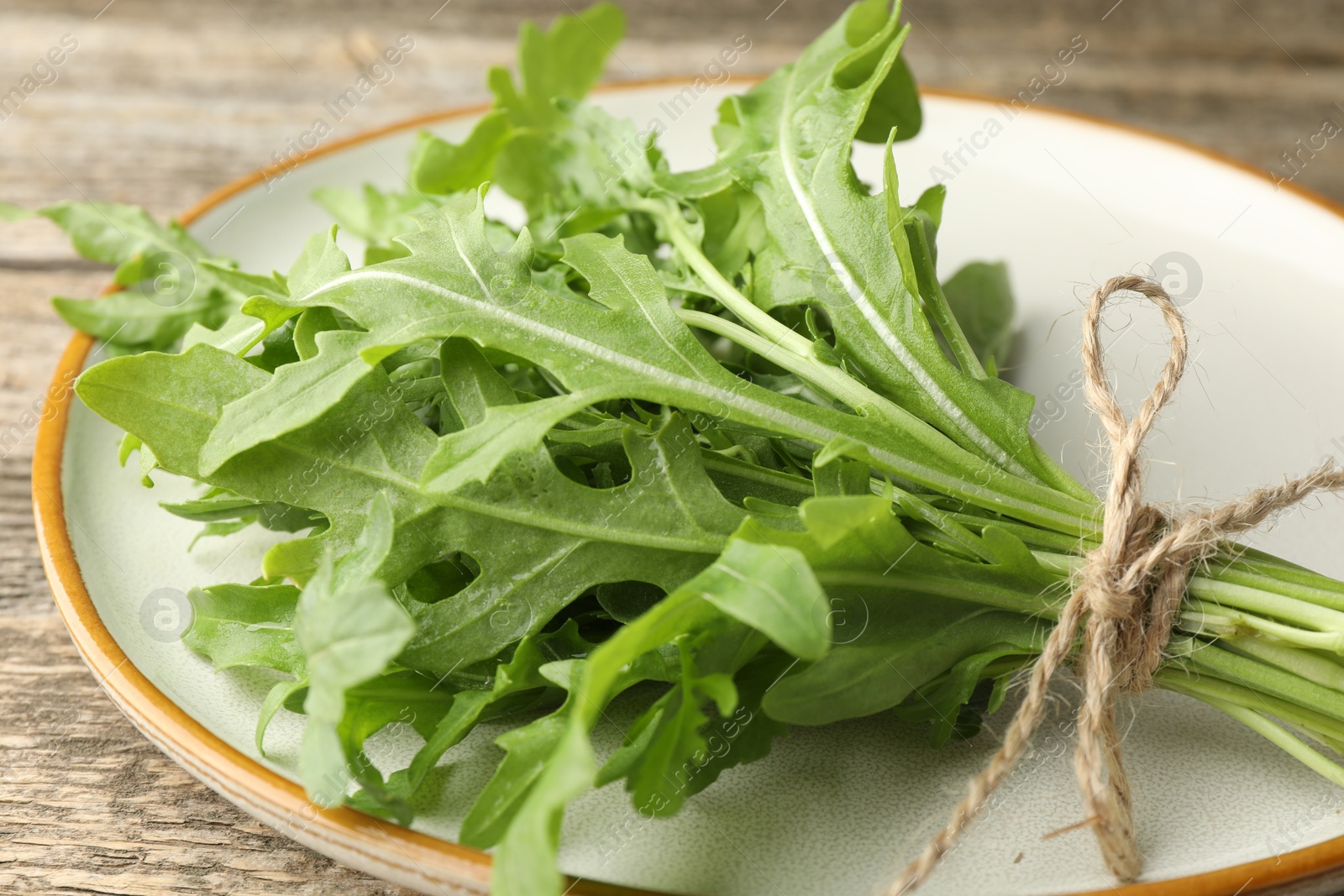 Photo of Bunch of fresh green arugula leaves on wooden table, closeup