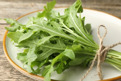 Photo of Bunch of fresh green arugula leaves on wooden table, closeup