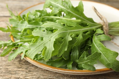 Photo of Bunch of fresh green arugula leaves on wooden table, closeup