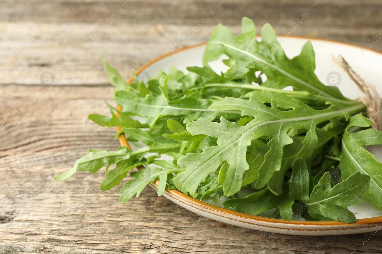 Photo of Fresh green arugula leaves on wooden table, closeup