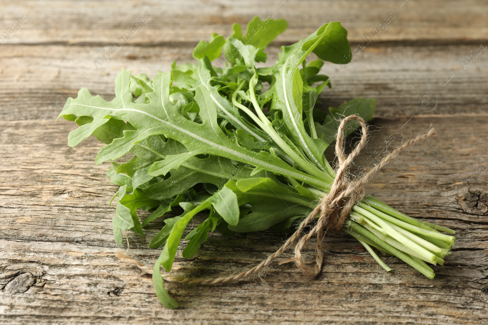 Photo of Bunch of fresh green arugula leaves on wooden table, closeup