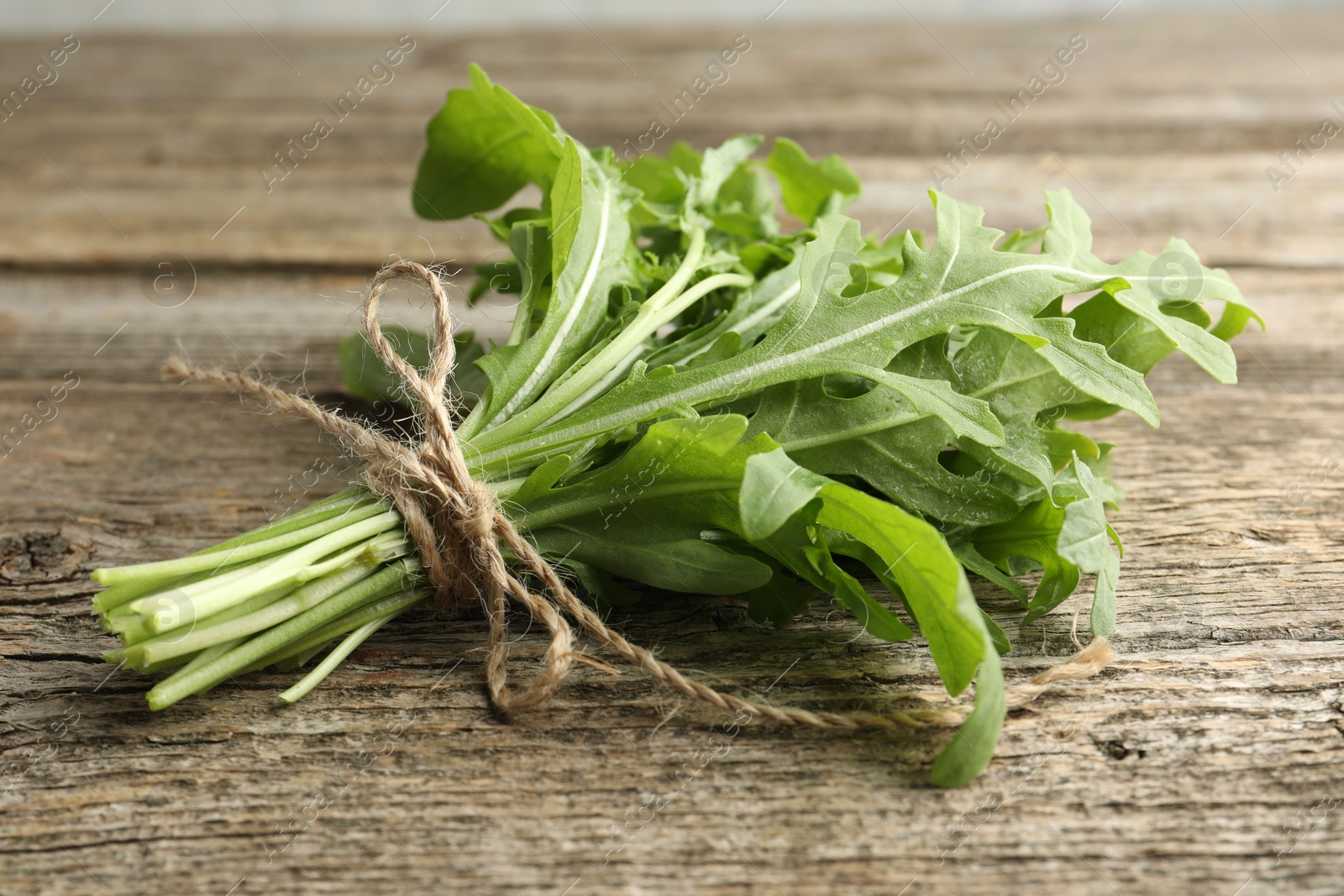 Photo of Bunch of fresh green arugula leaves on wooden table, closeup