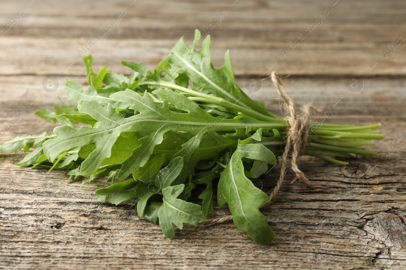 Photo of Bunch of fresh green arugula leaves on wooden table, closeup