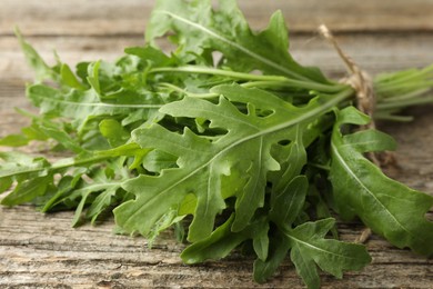 Photo of Bunch of fresh green arugula leaves on wooden table, closeup