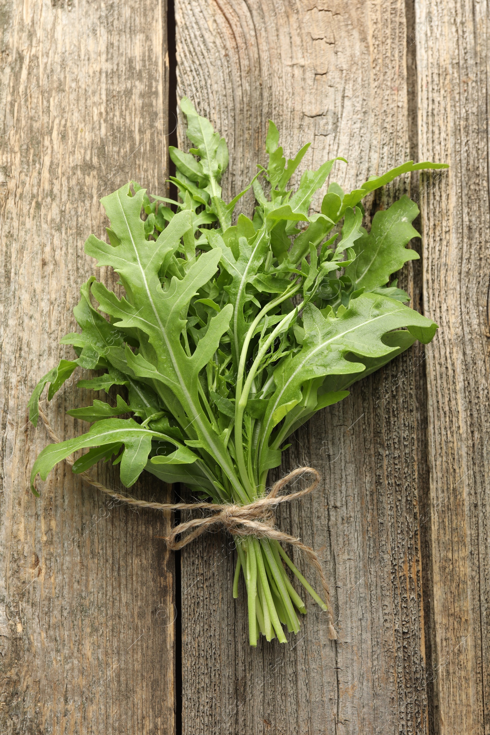 Photo of Bunch of fresh green arugula leaves on wooden table, top view