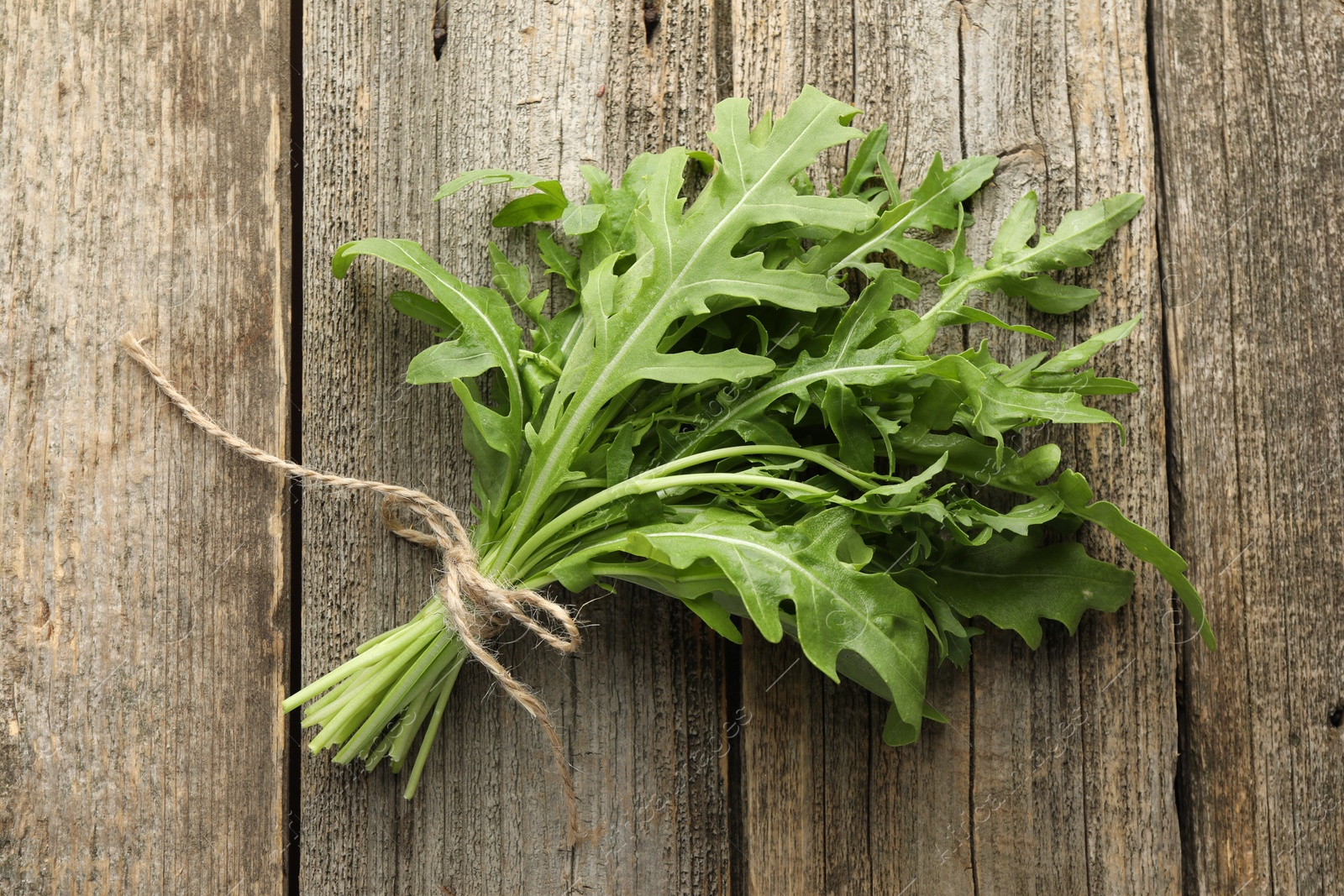 Photo of Bunch of fresh green arugula leaves on wooden table, top view