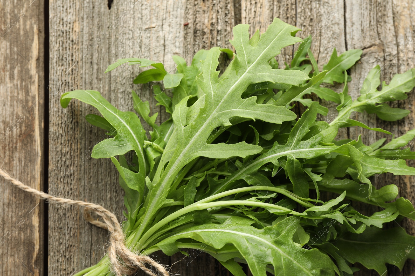 Photo of Bunch of fresh green arugula leaves on wooden table, top view