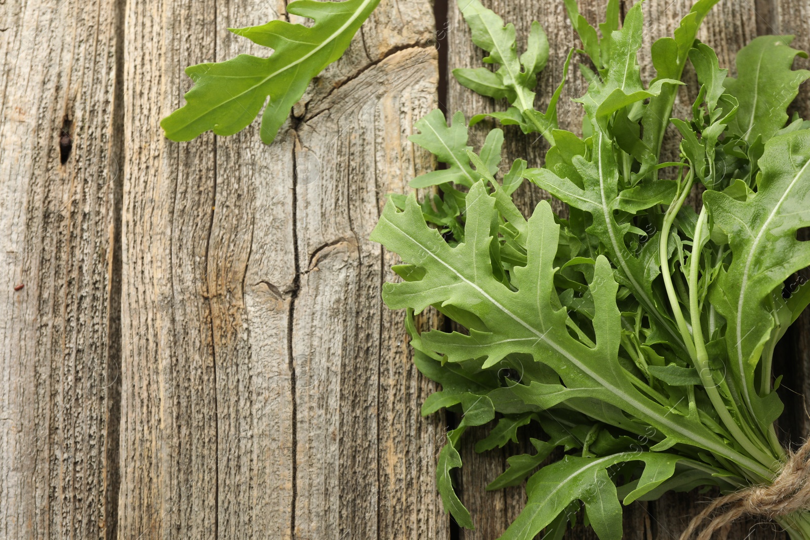 Photo of Bunch of fresh green arugula leaves on wooden table, top view. Space for text