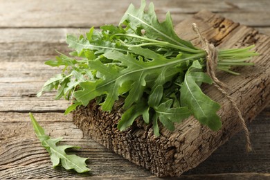 Photo of Bunch of fresh green arugula leaves on wooden table, closeup