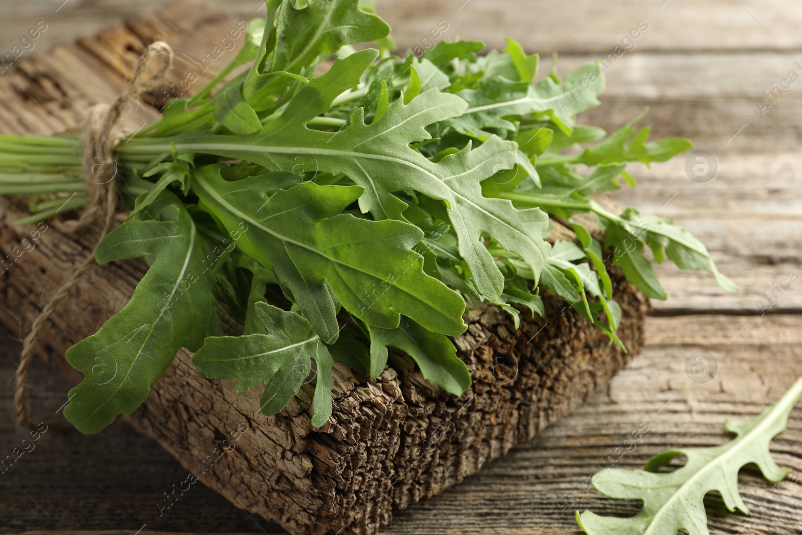 Photo of Bunch of fresh green arugula leaves on wooden table, closeup