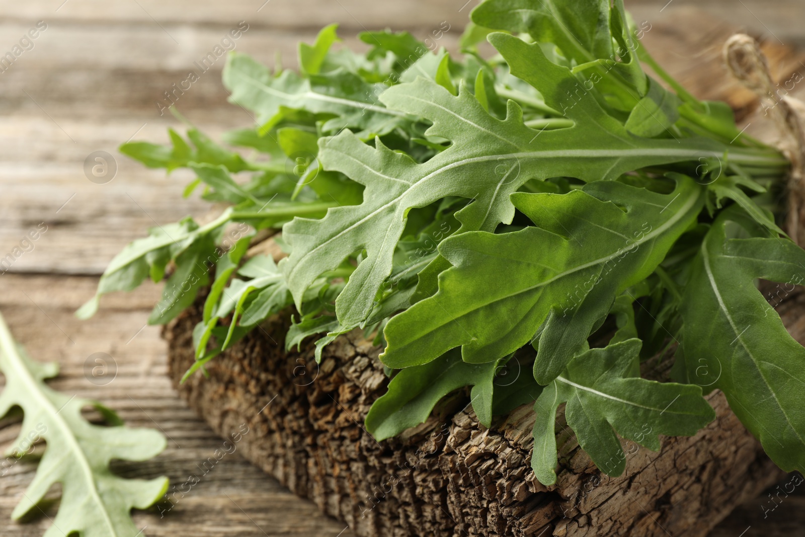 Photo of Bunch of fresh green arugula leaves on wooden table, closeup