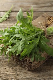 Photo of Bunch of fresh green arugula leaves on wooden table, closeup