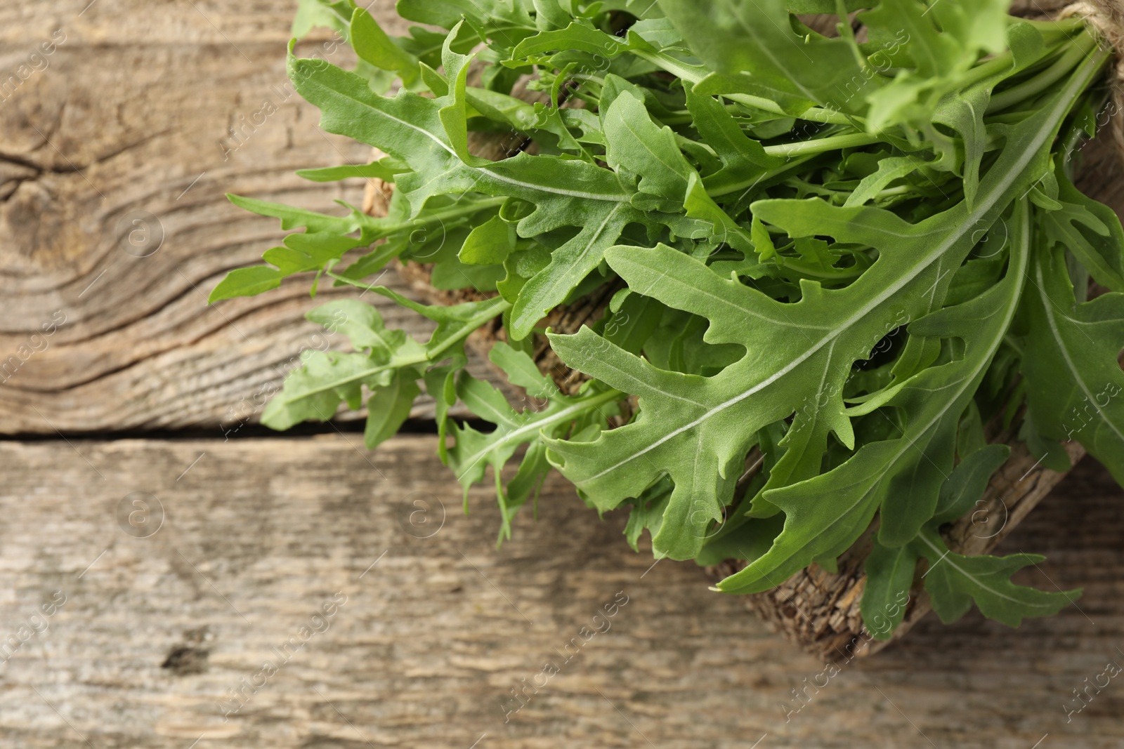 Photo of Fresh green arugula leaves on wooden table, closeup. Space for text