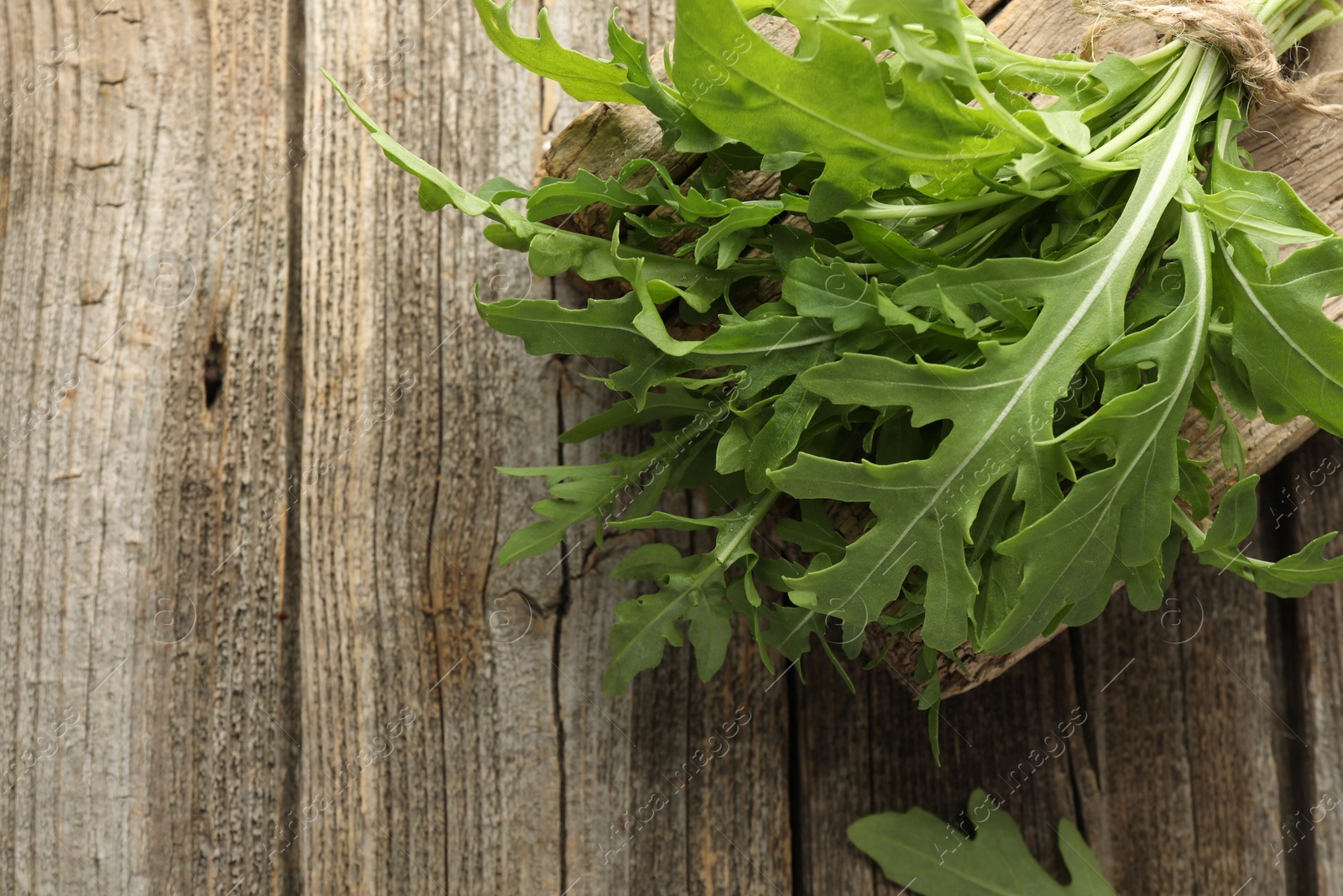 Photo of Bunch of fresh green arugula leaves on wooden table, top view. Space for text