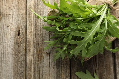 Photo of Bunch of fresh green arugula leaves on wooden table, top view. Space for text