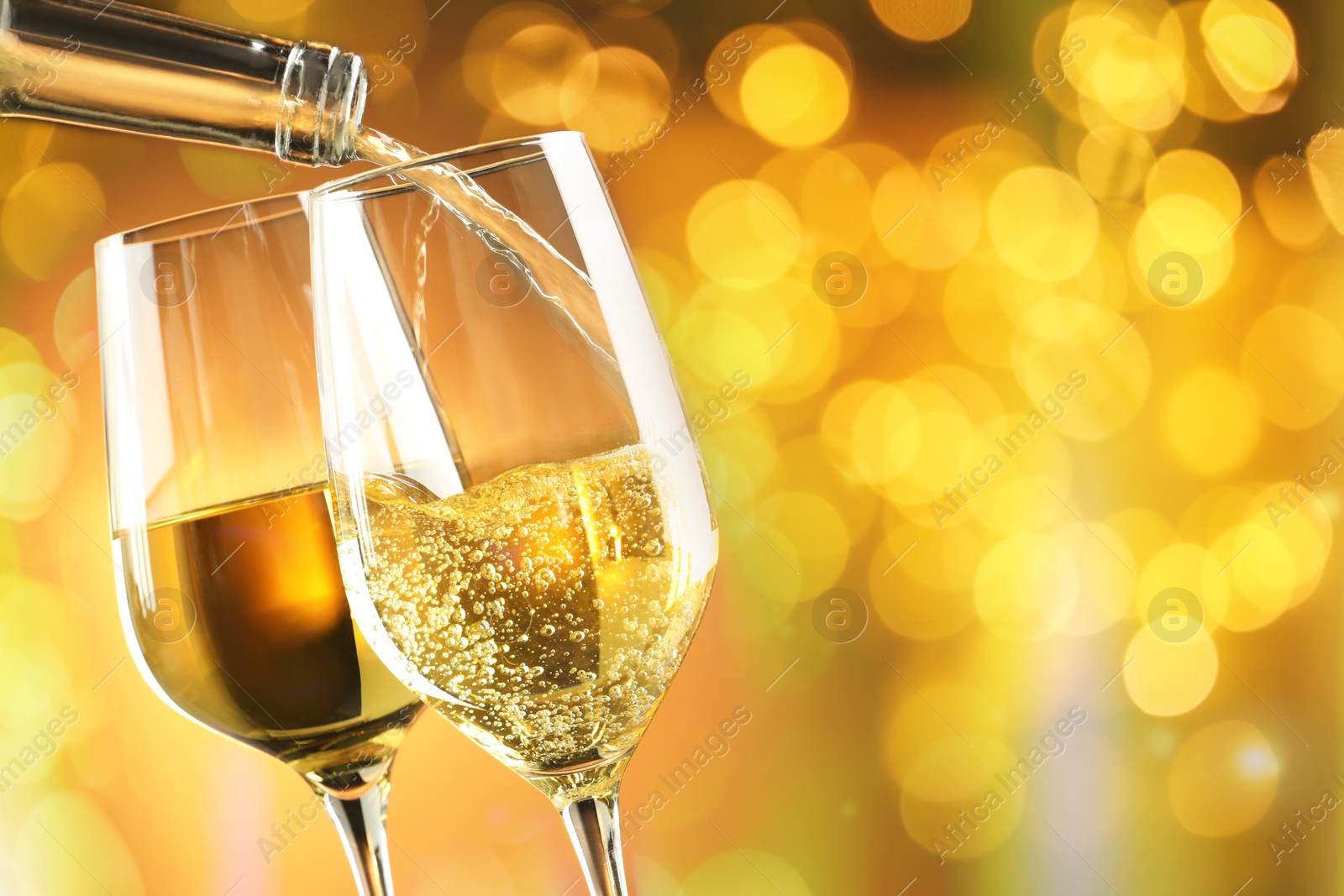 Image of Pouring tasty wine into glass against blurred lights, closeup. Bokeh effect