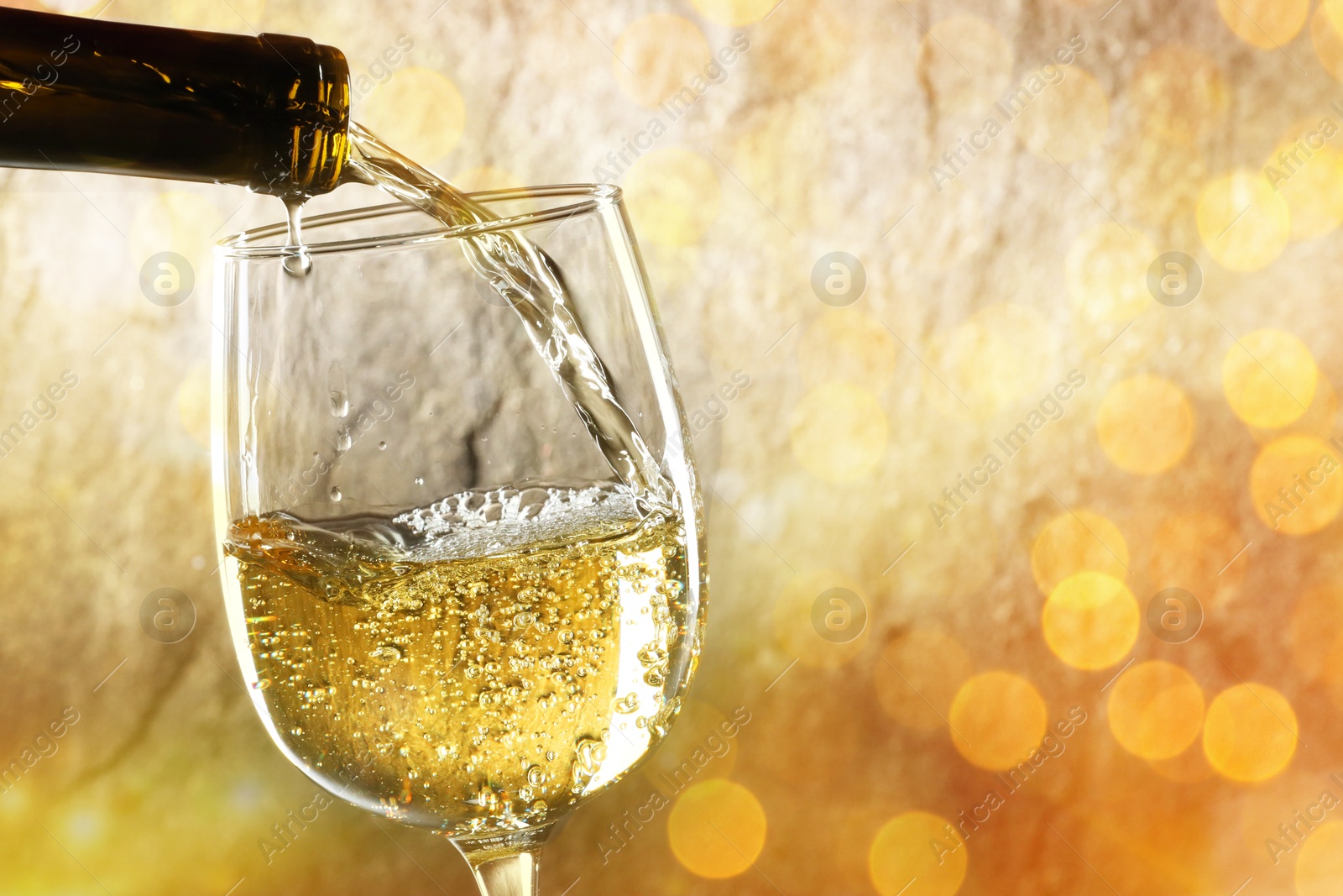 Image of Pouring tasty wine into glass against blurred lights, closeup. Bokeh effect