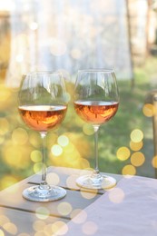 Image of Rose wine in glasses on wooden table in garden. Bokeh effect