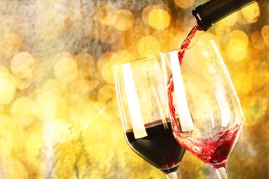 Image of Pouring red wine into glass against grey background, closeup. Bokeh effect