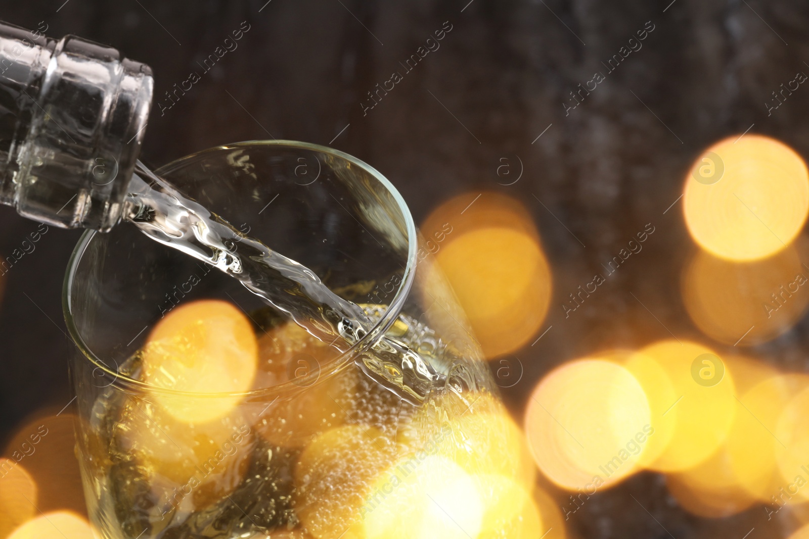 Image of Pouring white wine into glass, closeup. Bokeh effect