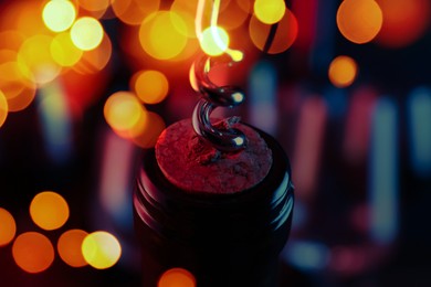 Opening wine bottle with corkscrew on blurred background, closeup. Bokeh effect