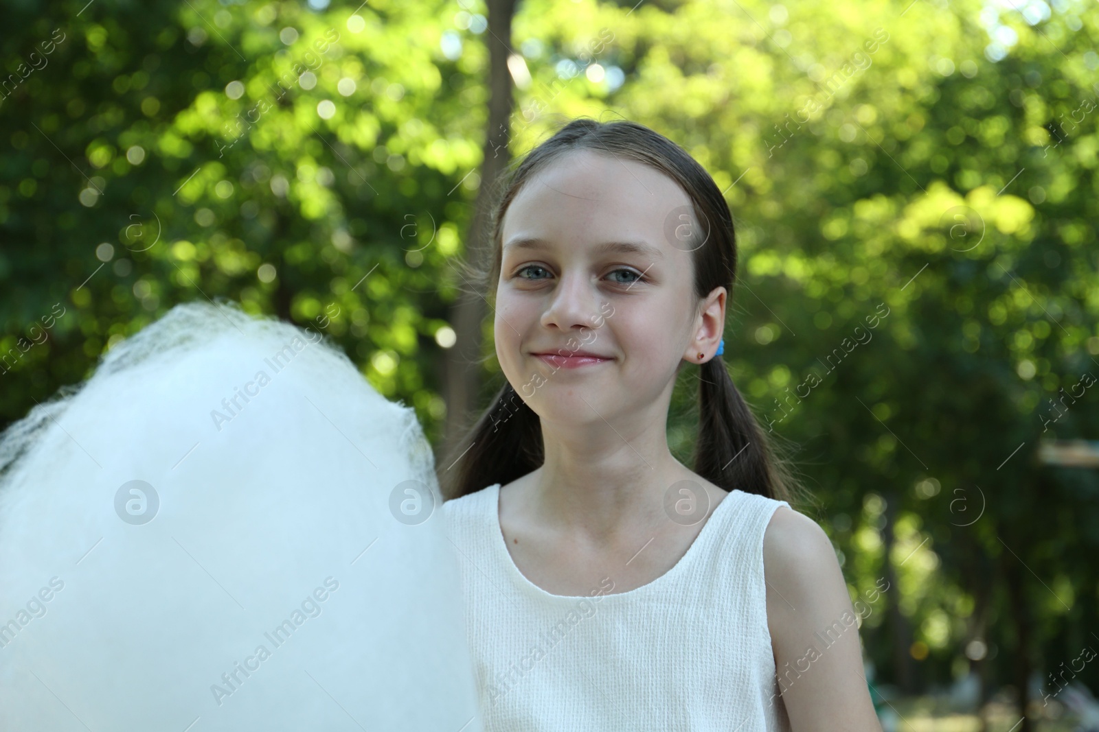 Photo of Portrait of little girl with sweet cotton candy in park