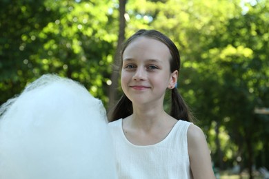 Portrait of little girl with sweet cotton candy in park