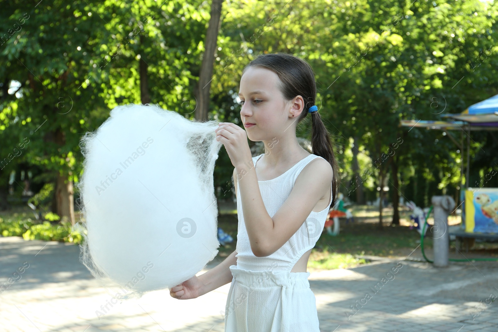 Photo of Little girl eating sweet cotton candy in park