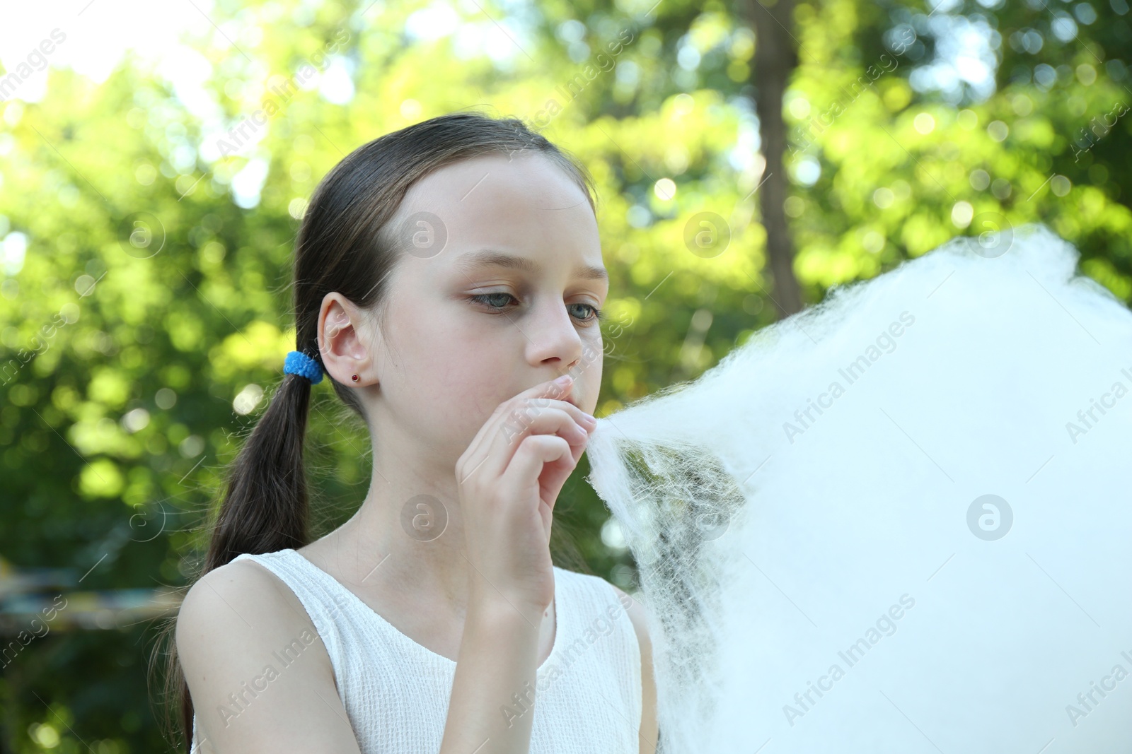 Photo of Little girl eating sweet cotton candy in park