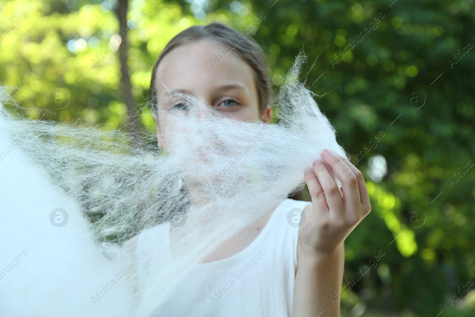 Photo of Little girl eating sweet cotton candy in park