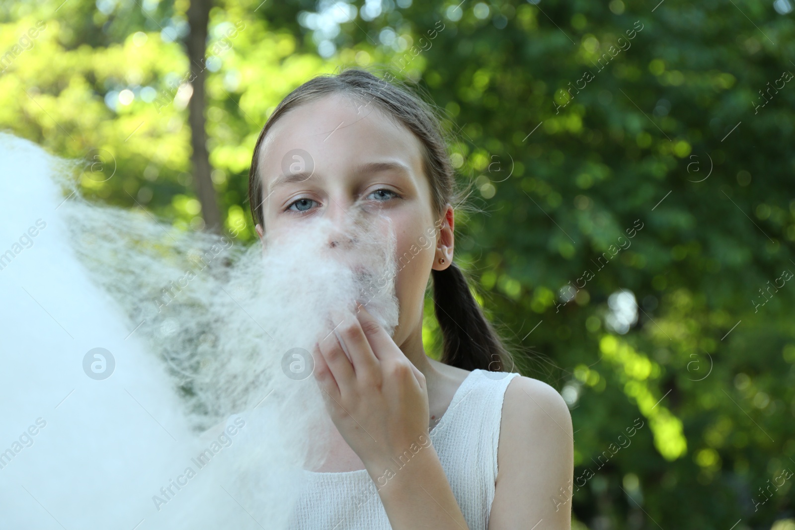 Photo of Little girl eating sweet cotton candy in park