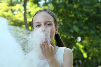 Photo of Little girl eating sweet cotton candy in park