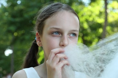 Photo of Little girl eating sweet cotton candy in park