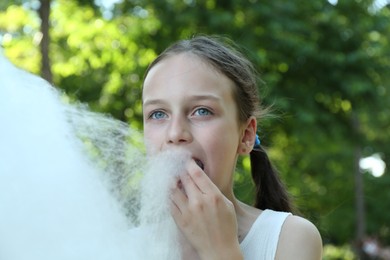 Photo of Little girl eating sweet cotton candy in park