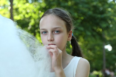 Photo of Little girl eating sweet cotton candy in park