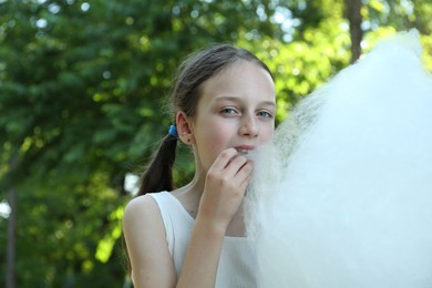 Photo of Little girl eating sweet cotton candy in park